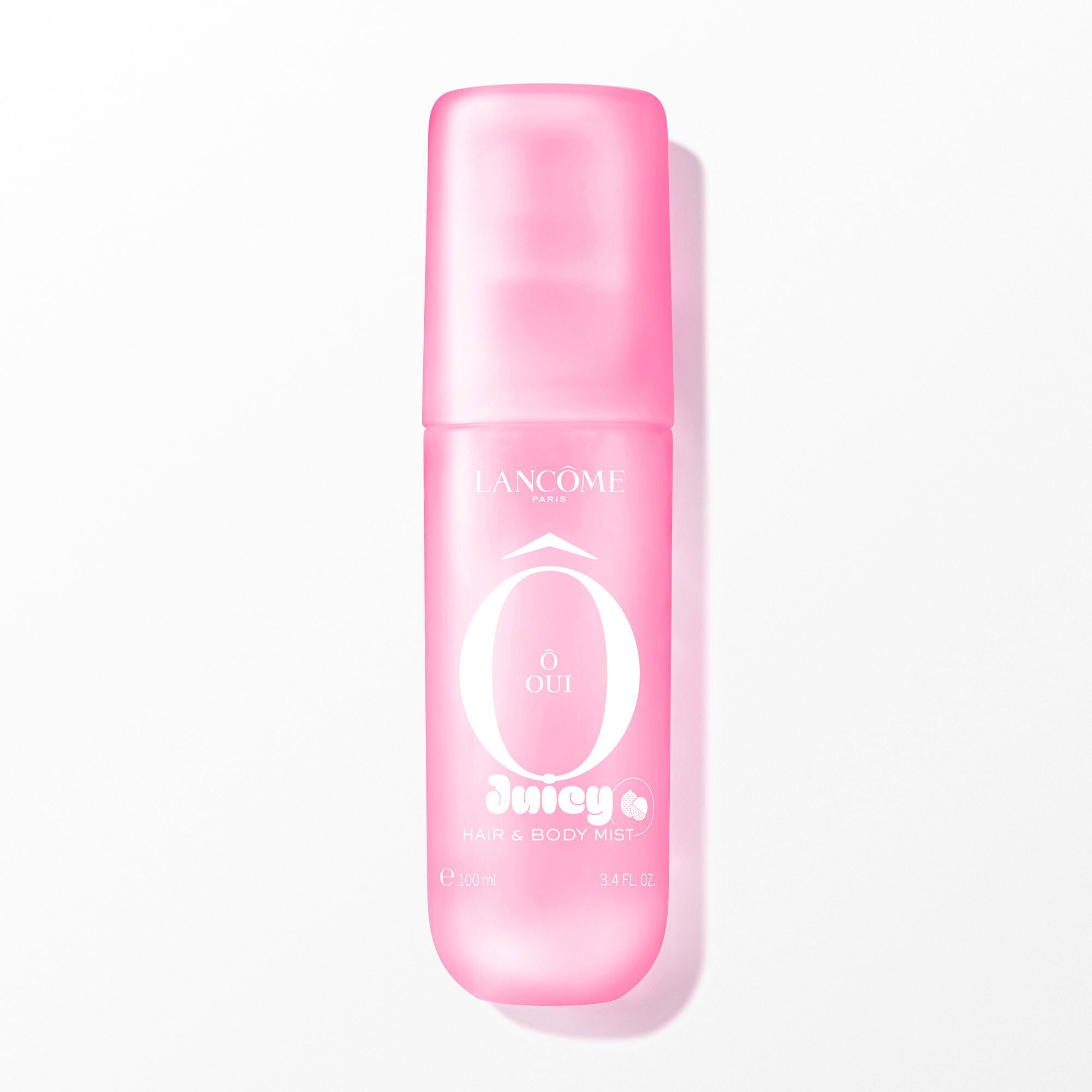 A pink transparent spray bottle with a soft touch finish, containing a clear liquid, with white text on the front. The bottle is positioned vertically in the center, casting a subtle shadow on the white background. The image is brightly lit from the front, with soft, even artificial lighting.
