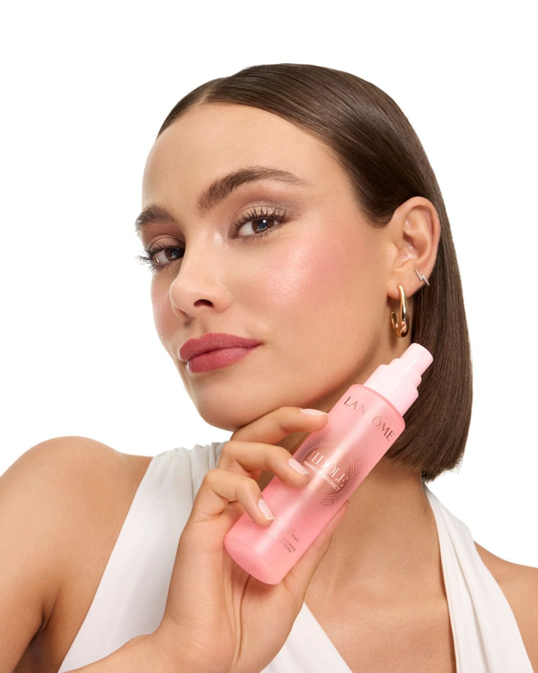 Woman with sleek bob holding Lancome Idole mist.